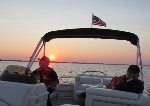 Two  persons in Auxiliary Uniforms sitting in a boat with the setting sun in the background