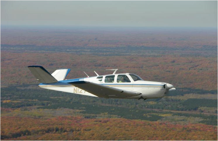 Blue and white plane in the Air  over forested area 